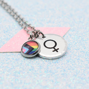 Necklace with a rainbow lgbtq pride flag charm and female gender symbol on a light blue background