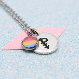 Necklace with a pansexual pride symbol and a black arrow on a pink triangle against a light blue background
