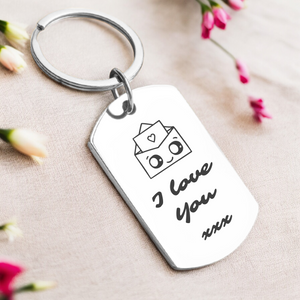 A personalized key ring with a silver or gold finish, featuring the phrase 'I love you' along with a personal message, presented in a box with flowers in the background.