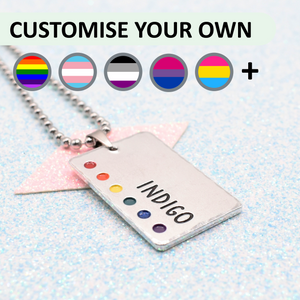 Customisable LGBTQ+ Pride Necklace featuring enamels of the traditional pride flag and a personalised name mounted on a ball chain displayed on a blue sparkle background