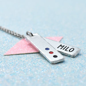 Customisable lgbtq pride pendant with polyamory pride colours and 'MILO' engraved, on a light blue background.
