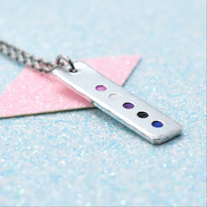 A minimalist pride necklace with a geometric shaped pendant featuring the gender fluid flag colours, attached to a silver-coloured chain.