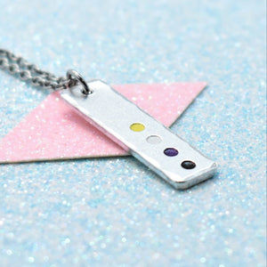 A minimalist pride necklace with a geometric shaped pendant featuring the non binary flag colours, attached to a silver chain.
