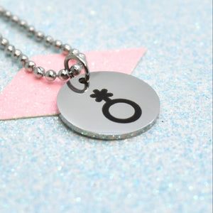 Necklace with a round silver pendant featuring a non binary symbol on a light blue and pink background