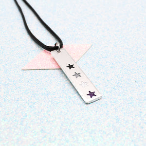 LGBTQ+ asexual Necklace bar pendant featuring colourful star designs representing the asexual pride flag on a light blue background on a faux leather cord