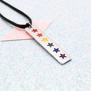 LGBTQ+ Rainbow Necklace bar pendant featuring colourful star designs representing the traditional pride flag on a light blue background on a faux leather cord