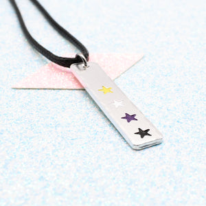 LGBTQ+ non binary Necklace bar pendant featuring colourful star designs representing the non binary pride flag on a light blue background on a faux leather cord
