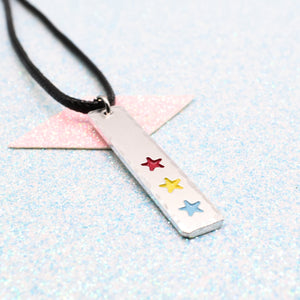LGBTQ+ pansexual Necklace bar pendant featuring colourful star designs representing the pansexual pride flag on a light blue background on a faux leather cord