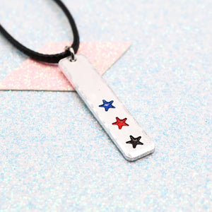 LGBTQ+ polyamorous Necklace bar pendant featuring colourful star designs representing the polyamorous pride flag on a light blue background on a faux leather cord