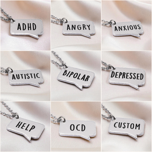 Collection of silver necklaces with speech bubble pendants displaying various labels.