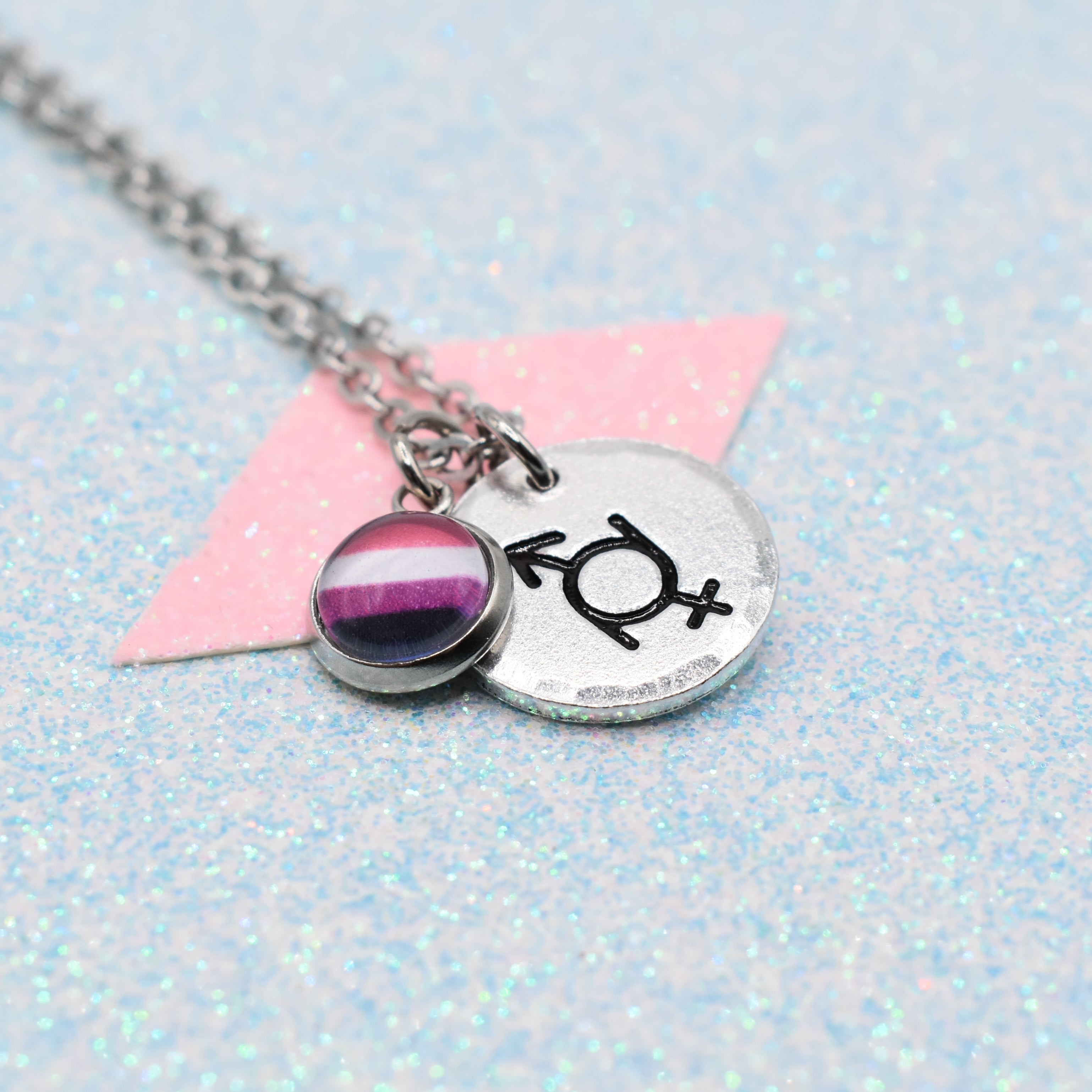 Gender Fluid Pride Symbol Necklace with Pride Flag charm on a glittery surface