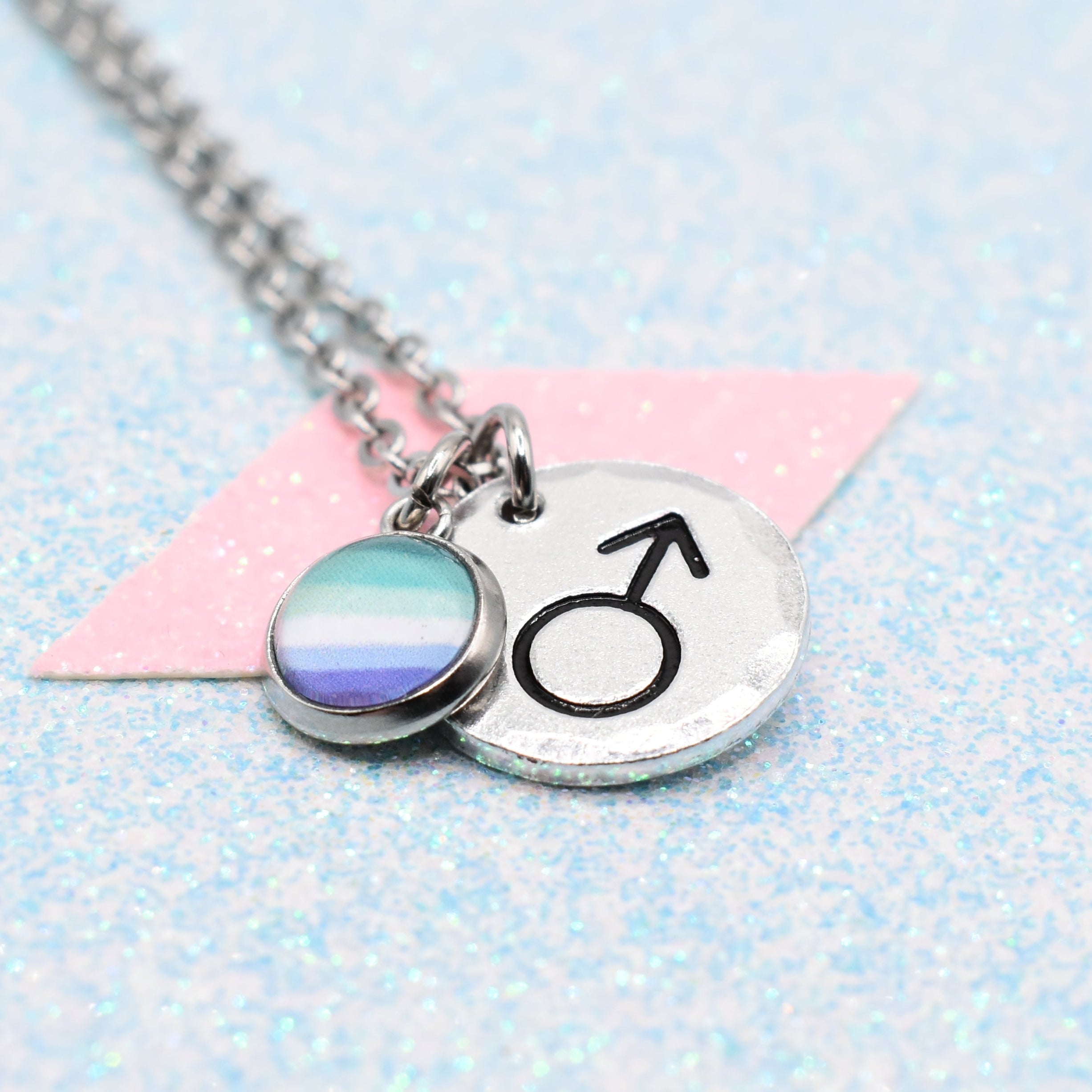 MLM Pride Necklace with a gender symbol charm on a light blue and pink background
