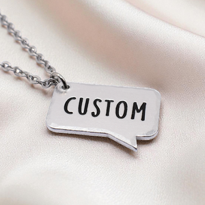 Silver necklace with a pendant labeled 'CUSTOM' on a satin surface