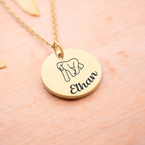 A gold-colored necklace with a personalized gorilla pendant featuring the name 'Ethan'.