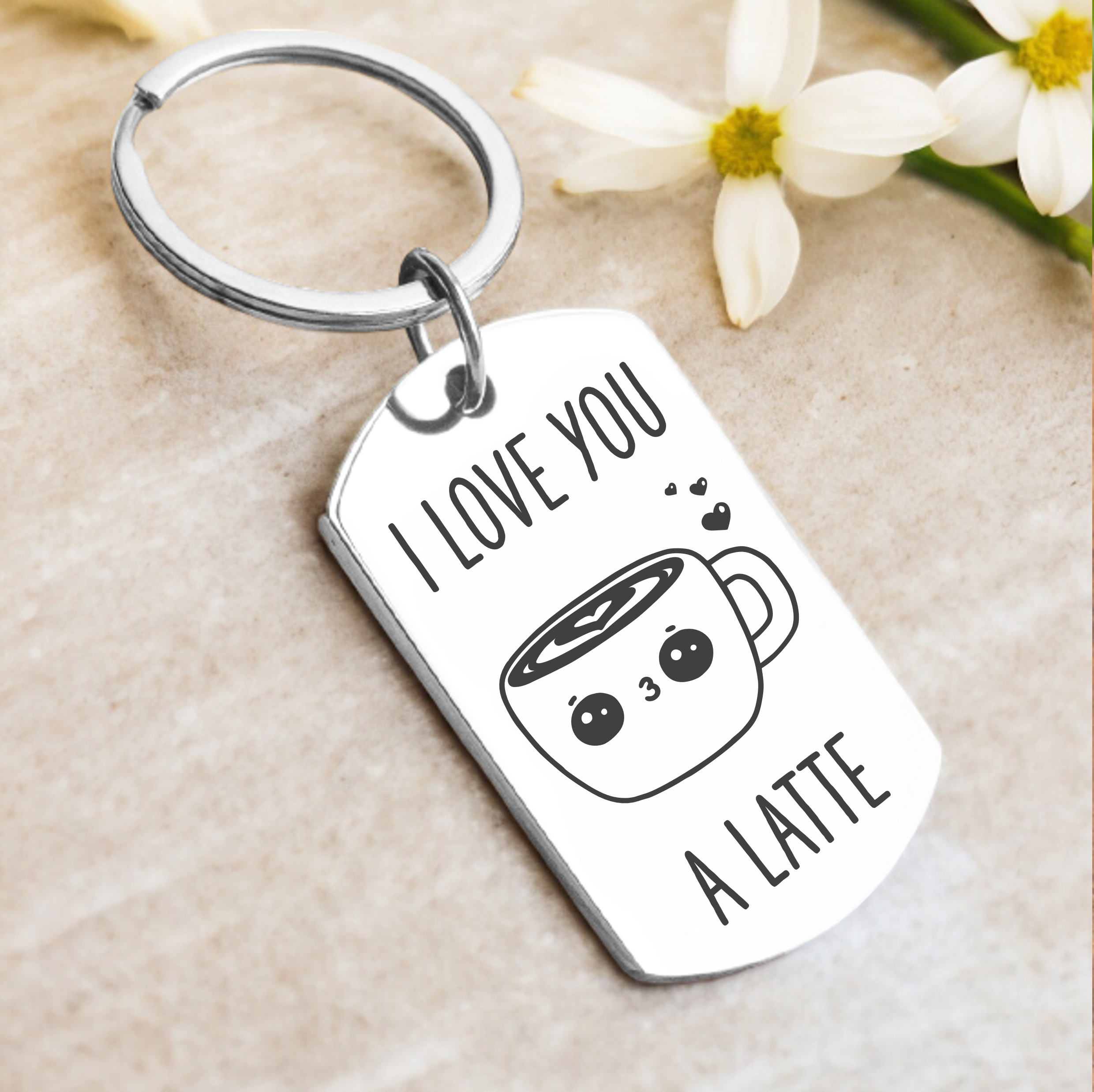 A key ring with a rectangular charm featuring the text 'I LOVE YOU A LATTE' and an illustration of a latte cup with a face. The charm is silver-colored with a mirrored finish.