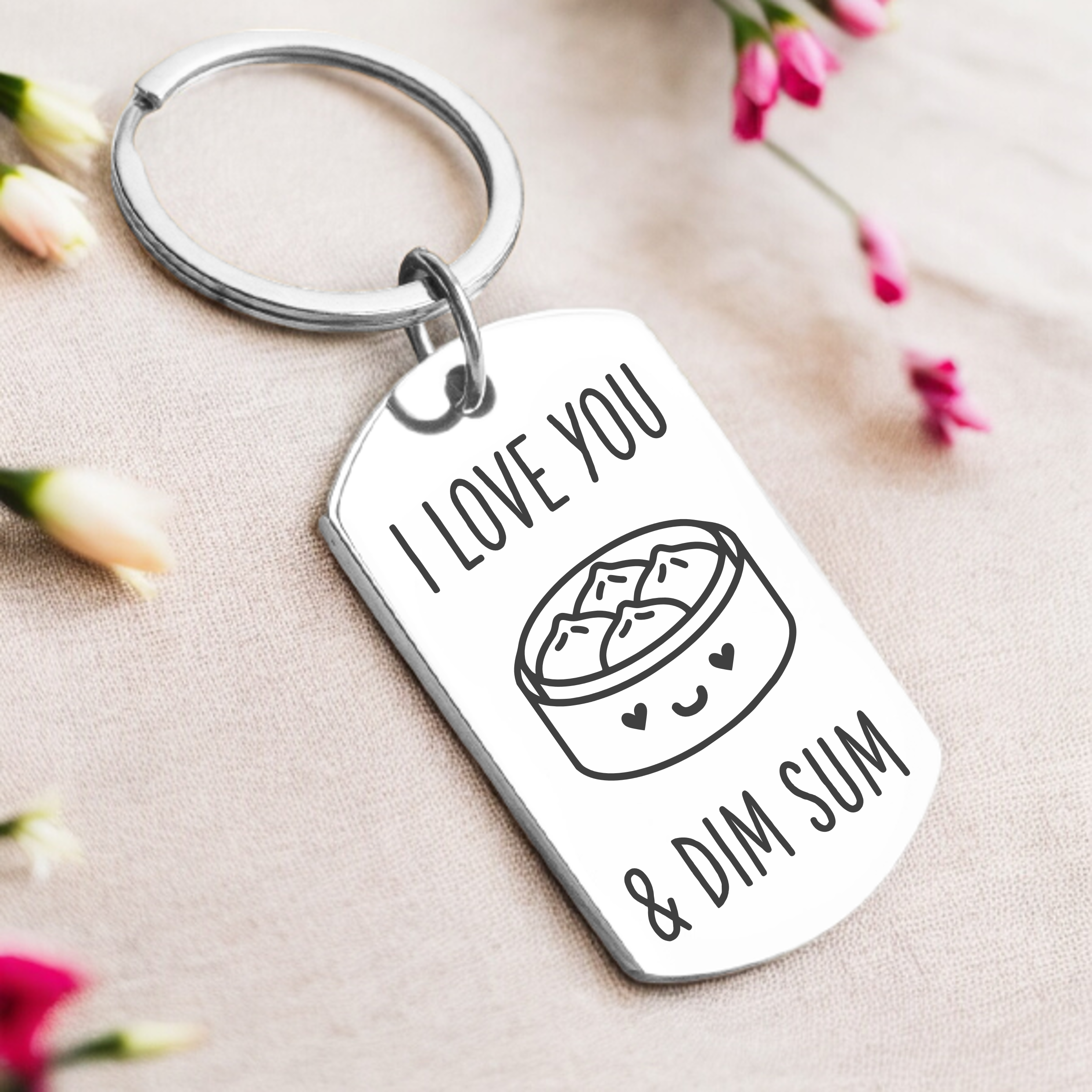 A key ring with a silver or gold tag, featuring the text 'I love you and dim sum' and a graphic of a dim sum basket.