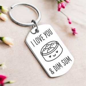 A key ring with a silver or gold tag, featuring the text 'I love you and dim sum' and a graphic of a dim sum basket.