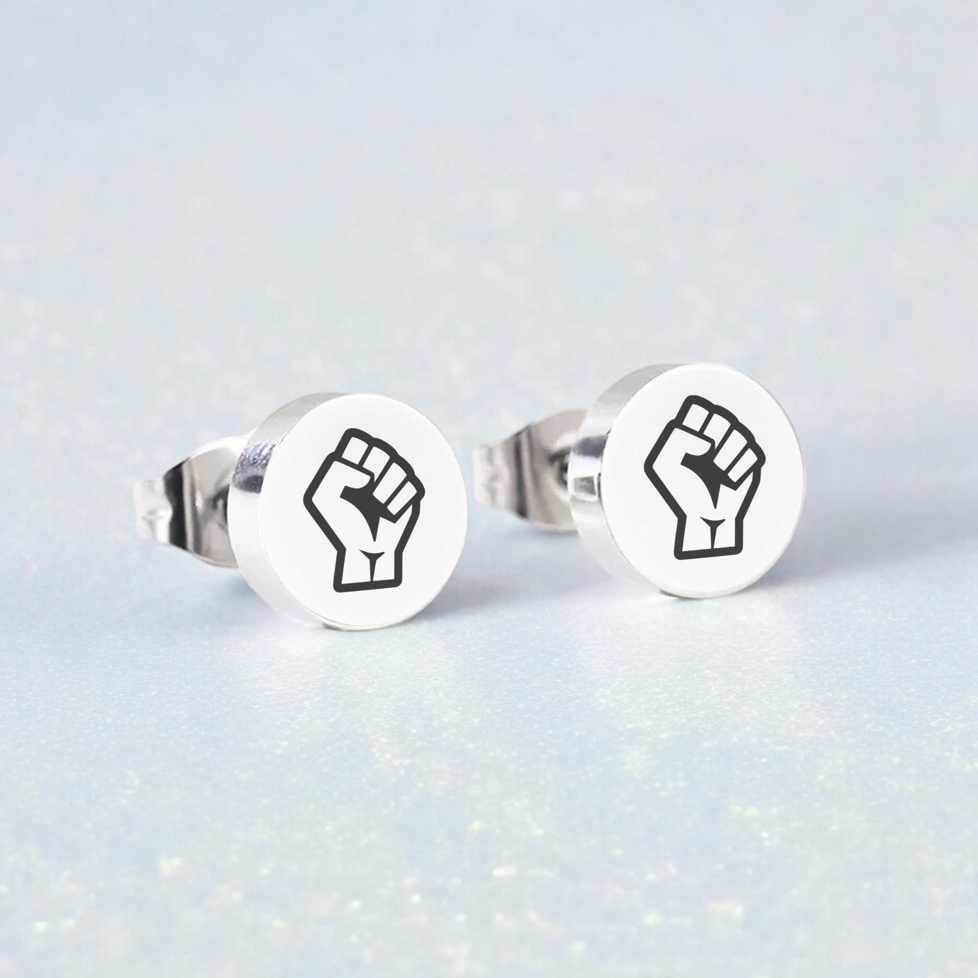 Pair of earring studs with Resist Fist Logo on blue background