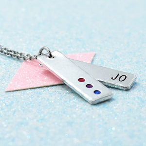 A minimalist personalised bisexual pride necklace with an enamelled pendant in the colors of the bisexual pride flag, attached to a cable chain. The pendant features the name 'Jo' with a date '08.