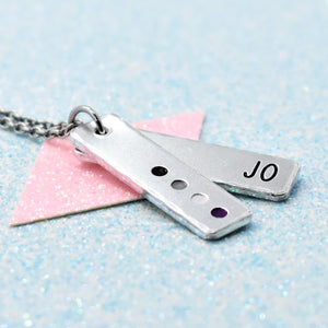 A personalised asexual pride necklace with a minimalist design, featuring a silver-colored pendant enamelled with the flag colors and the name 'Jo'.