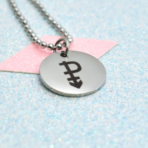 The image shows a silver-coloured necklace with a pendant featuring a black pansexual emblem. The pendant is round and has a shiny, metallic finish.