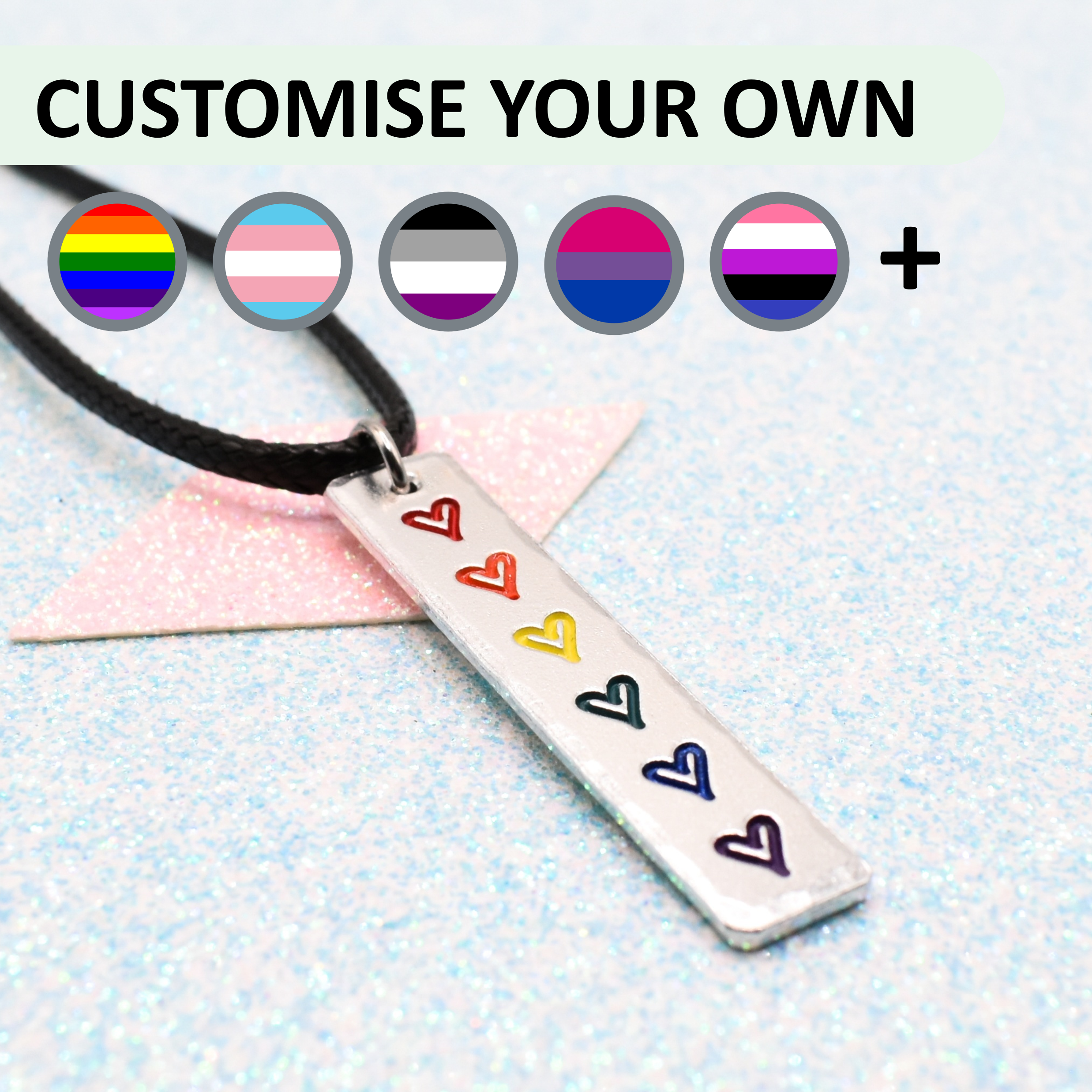 Customisable necklace with lgbtq pride rainbow-colored hearts enamelled in the colours of the pride flag on a light blue background.
