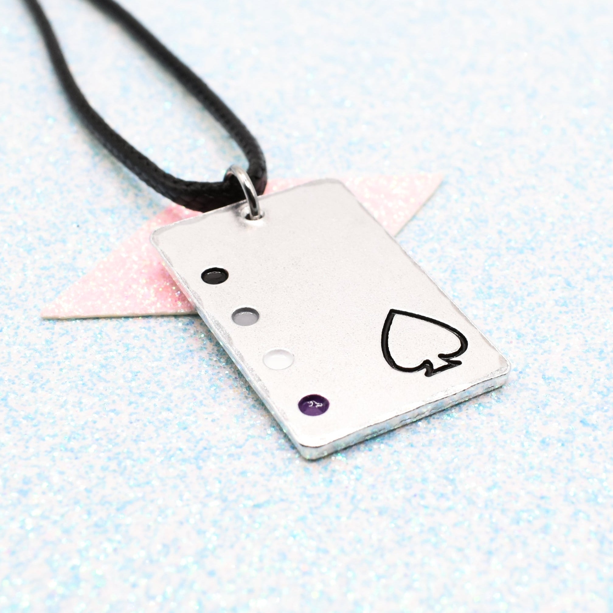 Asexual Necklace with a rectangular tag featuring a Asexual symbol and accents on a leather cord displayed on a light blue background