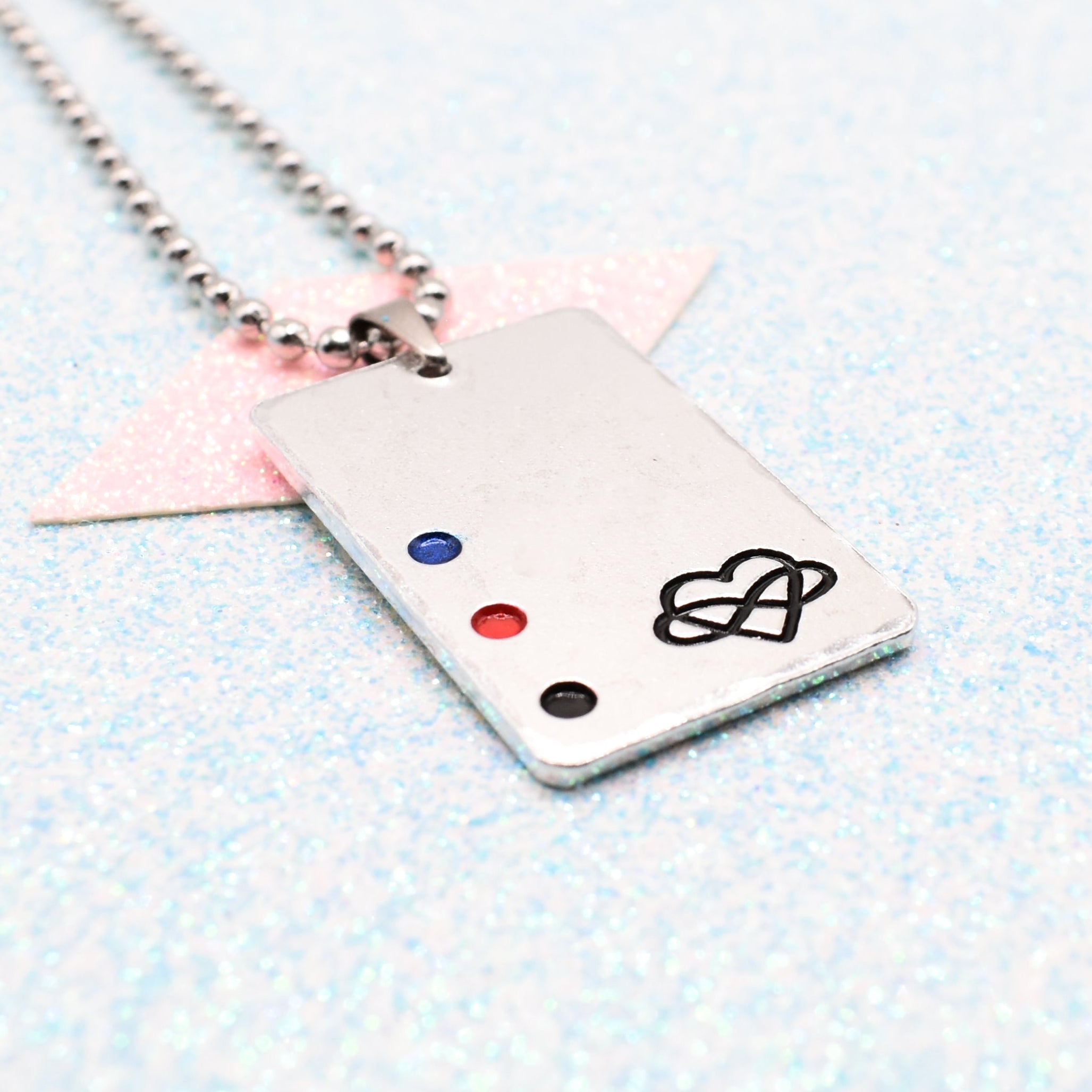 Polyamory Necklace with a rectangular tag featuring a polyamorous symbol and accents on a ball chain displayed on a light blue background