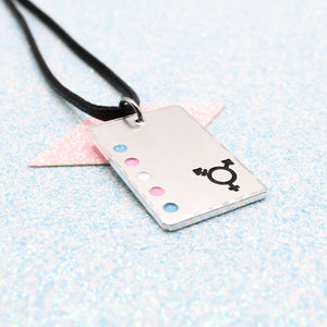 Transgender Necklace with a rectangular tag featuring a transgender symbol and accents on a leather cord displayed on a light blue background
